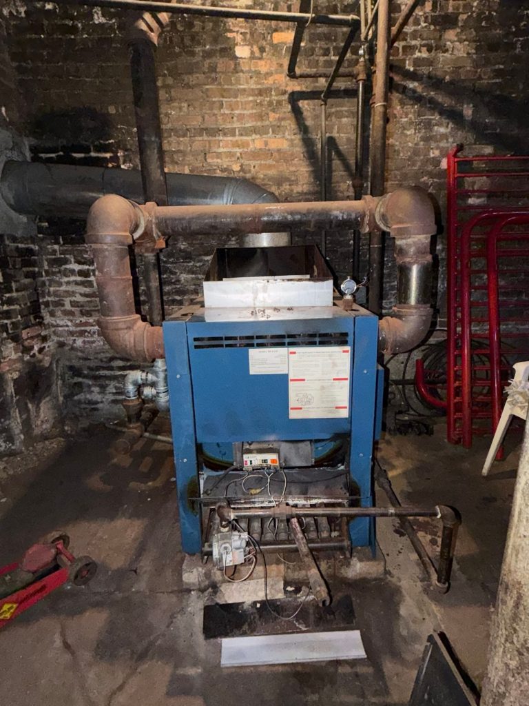 Old oversized steam boiler with incorrect piping in a Chicago three-flat basement
